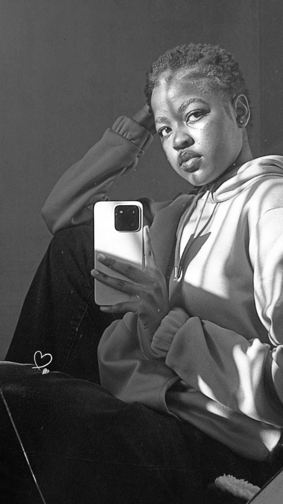 Black and white mirror portrait in a hoodie, seated, looking directly at the camera.