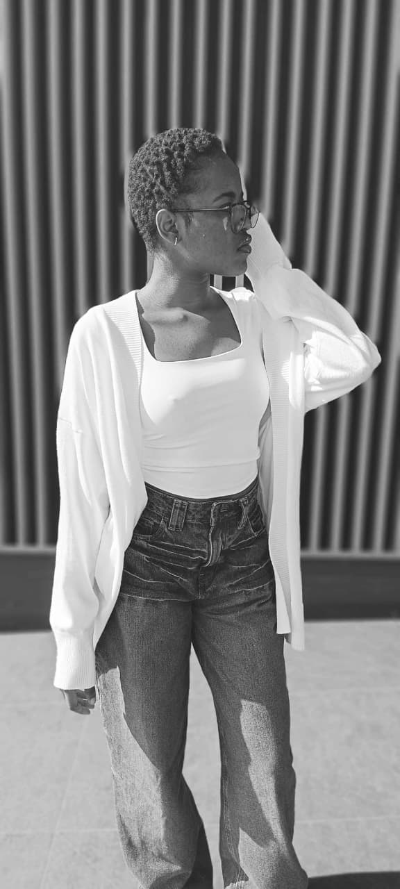 Black and white close beauty portrait against a corrugated wall, wearing glasses.