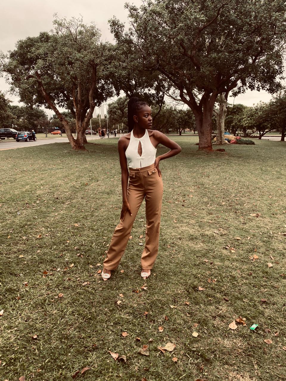 Fashion look: white cutout halter top and camel trousers, shot in a city park.